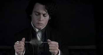 Movie still from “Sleepy Hollow” (1999), directed by Tim Burton – A man wearing a suit and tie holding a pair of whiskers; Close Up shot, High angle