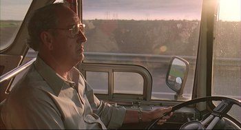 Movie still from “Bottle Rocket” (1996), directed by Wes Anderson – An older man driving a bus on the road; Close Up shot, Low angle