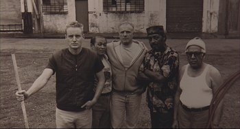Movie still from “Bottle Rocket” (1996), directed by Wes Anderson – A black and white photo of a group of people; Medium shot, High angle
