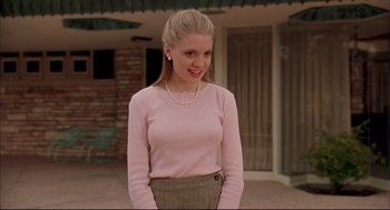 Movie still from “Bottle Rocket” (1996), directed by Wes Anderson – A woman in a pink shirt and a brown skirt; Medium shot, Low angle