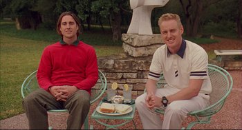 Movie still from “Bottle Rocket” (1996), directed by Wes Anderson – Two young men sitting on chairs in front of a cross; Medium shot, Low angle