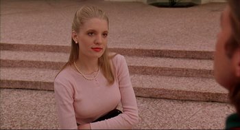 Movie still from “Bottle Rocket” (1996), directed by Wes Anderson – A woman in a pink dress sitting on some steps; Medium shot, Low angle