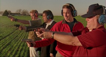 Movie still from “Bottle Rocket” (1996), directed by Wes Anderson – A group of people standing in a field holding guns; Medium shot, Low angle