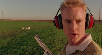 Movie still from “Bottle Rocket” (1996), directed by Wes Anderson – A man with a gun wearing ear muffs and headphones; Close Up shot, Low angle