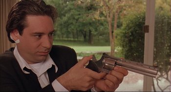 Movie still from “Bottle Rocket” (1996), directed by Wes Anderson – A man in a black suit holding a gun; Close Up shot, Low angle