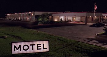 Movie still from “Bottle Rocket” (1996), directed by Wes Anderson – A motel sign in front of a building at night; Extreme Wide shot, Low angle