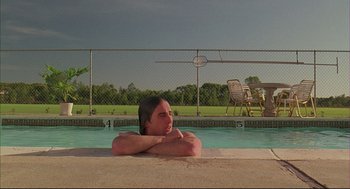 Movie still from “Bottle Rocket” (1996), directed by Wes Anderson – A woman sitting in a swimming pool with her arms folded over her head; Medium shot, Low angle