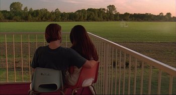 Movie still from “Bottle Rocket” (1996), directed by Wes Anderson – A man and a woman sitting on a chair looking out over a field; Wide shot, Over the shoulder angle