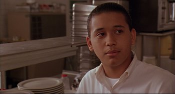 Movie still from “Bottle Rocket” (1996), directed by Wes Anderson – A young man in a kitchen with plates in the background; Close Up shot, Low angle