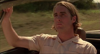 Movie still from “Bottle Rocket” (1996), directed by Wes Anderson – A man with long blonde hair is sitting in a car; Close Up shot, Low angle
