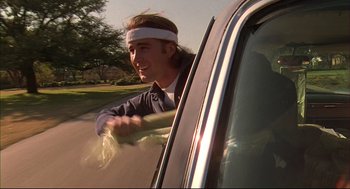 Movie still from “Bottle Rocket” (1996), directed by Wes Anderson – A man with a headband is driving a car; Medium shot, Low angle