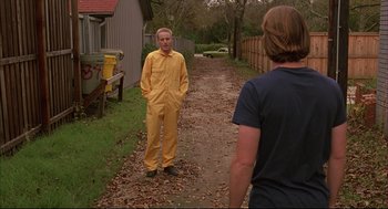 Movie still from “Bottle Rocket” (1996), directed by Wes Anderson – A man in yellow overalls standing next to another man; Medium shot, Over the shoulder angle