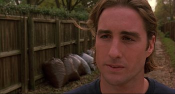 Movie still from “Bottle Rocket” (1996), directed by Wes Anderson – A person near a pile of trash bags; Close Up shot, Over the shoulder angle