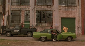 Movie still from “Bottle Rocket” (1996), directed by Wes Anderson – An old car parked on the side of the street; Wide shot, High angle