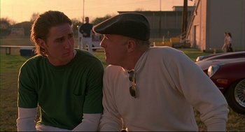 Movie still from “Bottle Rocket” (1996), directed by Wes Anderson – Two men sitting on a baseball field talking to each other; Close Up shot, Over the shoulder angle