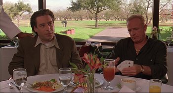 Movie still from “Bottle Rocket” (1996), directed by Wes Anderson – Two men sitting at a table with a plate of food in front of them; Medium shot, Over the shoulder angle