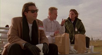 Movie still from “Bottle Rocket” (1996), directed by Wes Anderson – A group of men sitting next to each other on the ground; Medium shot, Low angle