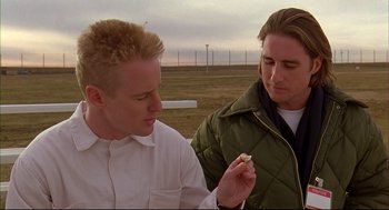 Movie still from “Bottle Rocket” (1996), directed by Wes Anderson – Two men standing next to each other on a field; Close Up shot, Over the shoulder angle
