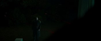 Movie still from “Snake Eyes” (2021), directed by Robert Schwentke – A man standing in the dark with a red light in the background; Wide shot, Over the shoulder angle