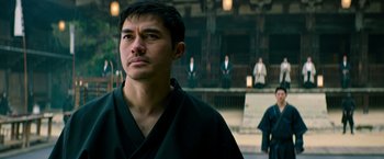 Movie still from “Snake Eyes” (2021), directed by Robert Schwentke – A man wearing a black robe looking to his left; Close Up shot, Low angle