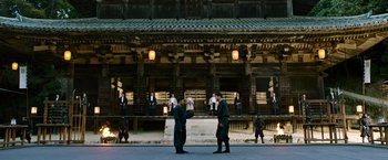 Movie still from “Snake Eyes” (2021), directed by Robert Schwentke – Two men are shaking hands in front of a building; Extreme Wide shot, Over the shoulder angle