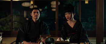 Movie still from “Snake Eyes” (2021), directed by Robert Schwentke – A man and a woman sitting at a table; Medium shot, Low angle