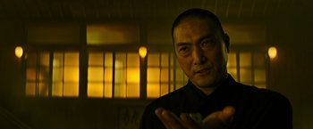 Movie still from “Snake Eyes” (2021), directed by Robert Schwentke – A man in a black shirt is looking at the camera; Close Up shot, Low angle