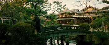 Movie still from “Snake Eyes” (2021), directed by Robert Schwentke – A man standing on a bridge over a river; Extreme Wide shot, High angle