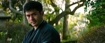 Movie still from “Snake Eyes” (2021), directed by Robert Schwentke – A young man in a black jacket stands in front of a tree; Close Up shot, Over the shoulder angle