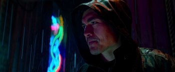 Movie still from “Snake Eyes” (2021), directed by Robert Schwentke – A man in a hooded jacket looking at a neon sign; Close Up shot, Low angle