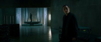 Movie still from “Snake Eyes” (2021), directed by Robert Schwentke – A man standing in an empty room holding a camera; Wide shot, Low angle