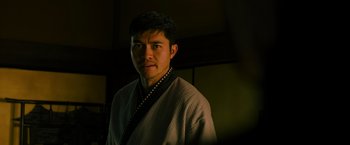 Movie still from “Snake Eyes” (2021), directed by Robert Schwentke – A man wearing a robe and holding a rosary; Close Up shot, Over the shoulder angle