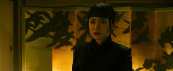 Movie still from “Snake Eyes” (2021), directed by Robert Schwentke – A woman in a black jacket standing in front of a wall; Close Up shot, Low angle