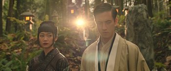 Movie still from “Snake Eyes” (2021), directed by Robert Schwentke – A man and a woman standing next to each other in a forest; Close Up shot, Low angle