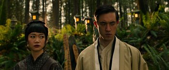 Movie still from “Snake Eyes” (2021), directed by Robert Schwentke – A man in a white shirt and a white tie standing in front of a forest; Close Up shot, Over the shoulder angle