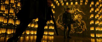 Movie still from “Snake Eyes” (2021), directed by Robert Schwentke – A man standing in front of an illuminated wall; Wide shot, Low angle