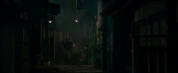 Movie still from “Snake Eyes” (2021), directed by Robert Schwentke – A man in a robe walking in a dark room; Wide shot, Low angle