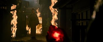 Movie still from “Snake Eyes” (2021), directed by Robert Schwentke – A man standing in front of a burning building; Extreme Wide shot, Low angle