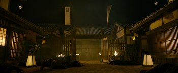Movie still from “Snake Eyes” (2021), directed by Robert Schwentke – A man standing in front of a gate at night; Extreme Wide shot, Low angle