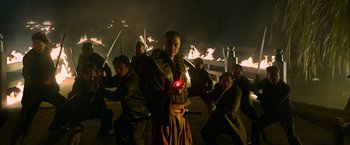 Movie still from “Snake Eyes” (2021), directed by Robert Schwentke – A group of people standing in front of a fire pit; Medium shot, Low angle