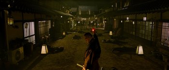 Movie still from “Snake Eyes” (2021), directed by Robert Schwentke – A man holding a red object in a room; Extreme Wide shot, High angle