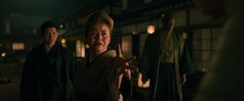 Movie still from “Snake Eyes” (2021), directed by Robert Schwentke – An older woman in traditional japanese garb holding out her hands; Medium shot, Low angle