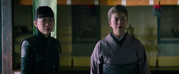Movie still from “Snake Eyes” (2021), directed by Robert Schwentke – Two women dressed in traditional japanese garb stand in front of a building; Close Up shot, Low angle