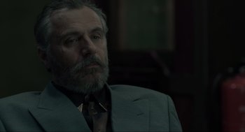 Movie still from “Snatch” (2000), directed by Guy Ritchie – An older man wearing a suit and a tie; Close Up shot, Over the shoulder angle