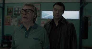 Movie still from “Snatch” (2000), directed by Guy Ritchie – Two men standing next to each other in front of a window; Medium shot, Over the shoulder angle