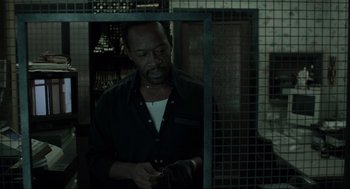 Movie still from “Snatch” (2000), directed by Guy Ritchie – A man standing in front of a metal cage; Medium shot, Over the shoulder angle
