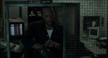 Movie still from “Snatch” (2000), directed by Guy Ritchie – A man holding a bag in a dark room; Medium shot, Over the shoulder angle