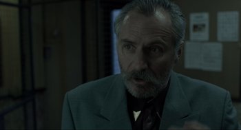 Movie still from “Snatch” (2000), directed by Guy Ritchie – An older man in a suit and tie looking at the camera; Close Up shot, Over the shoulder angle