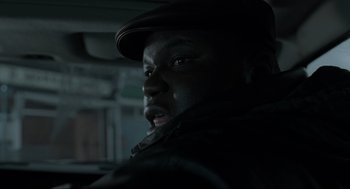 Movie still from “Snatch” (2000), directed by Guy Ritchie – A man with a hat is in the dark; Close Up shot, Over the shoulder angle