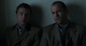 Movie still from “Snatch” (2000), directed by Guy Ritchie – A couple of men sitting next to each other in a room; Close Up shot, Low angle
